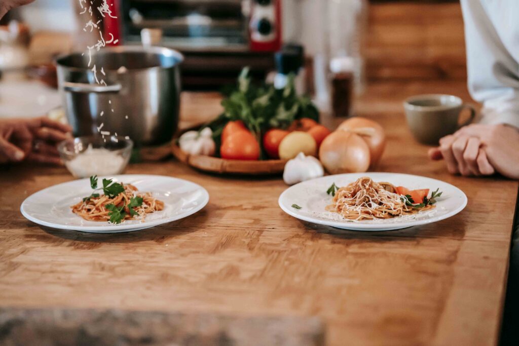 A close-up of pasta plates on a wooden counter, showcasing a messy cooking experiment for fun date night options.