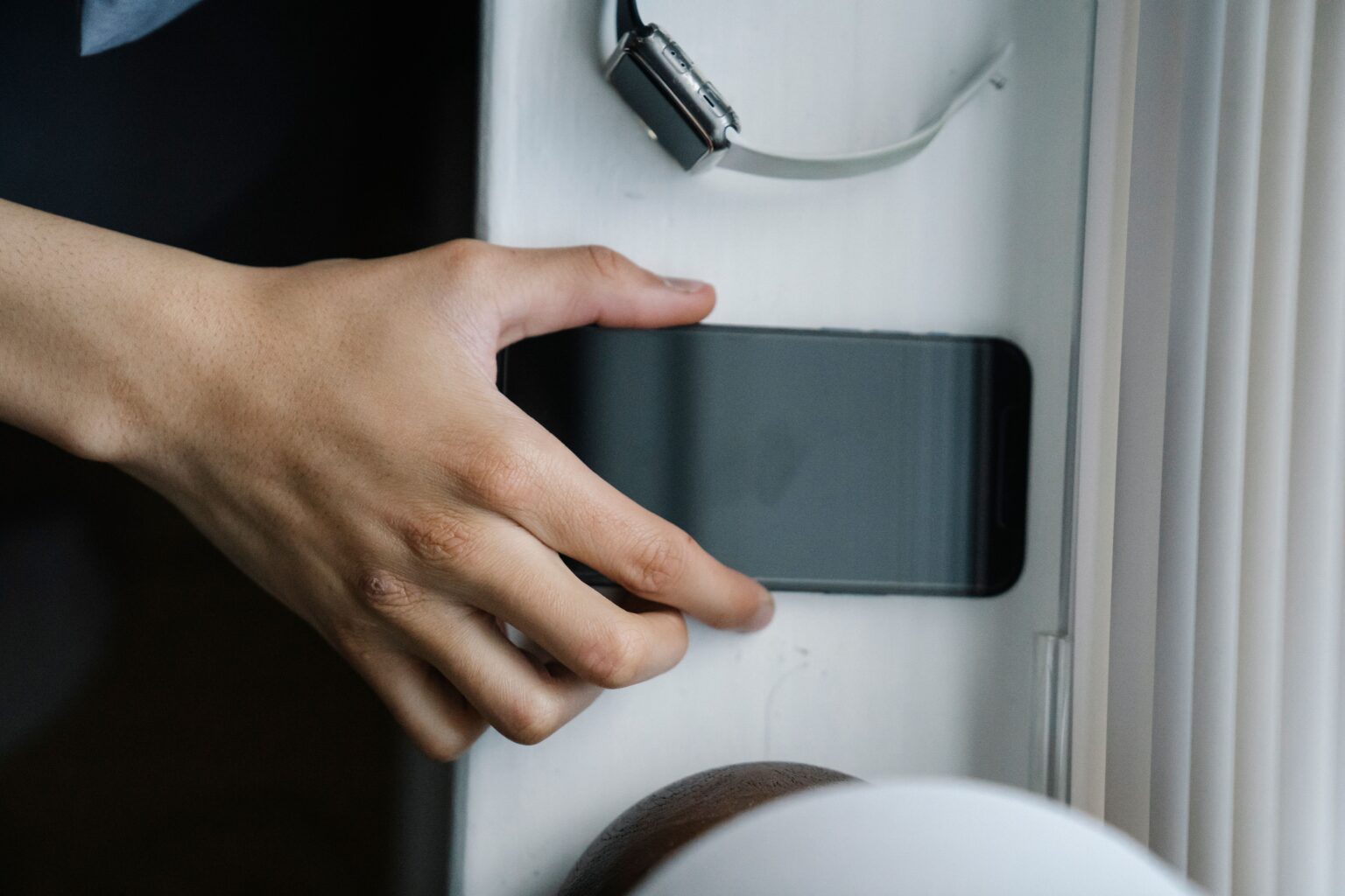 Life Is Too Short For Fake Friends: Here Is Your Sign To Finally Clean Out Your Inner Circle A close up of a hand pulling away a smartphone from a ledge, representing cutting off fake friends.