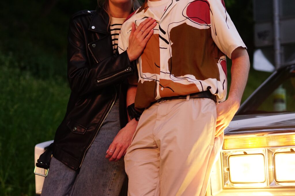 A close-up of a couple leaning on a car headlight at night, perfect for spontaneous date night setups.