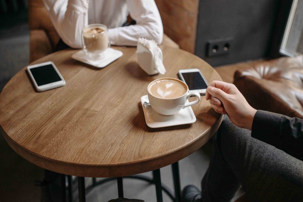 Close up of two people having coffee at a wooden table, reflecting a disconnect about family estrangement.