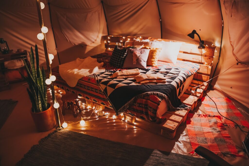 A magical indoor tent decorated with warm fairy lights for intimate cozy staycations.