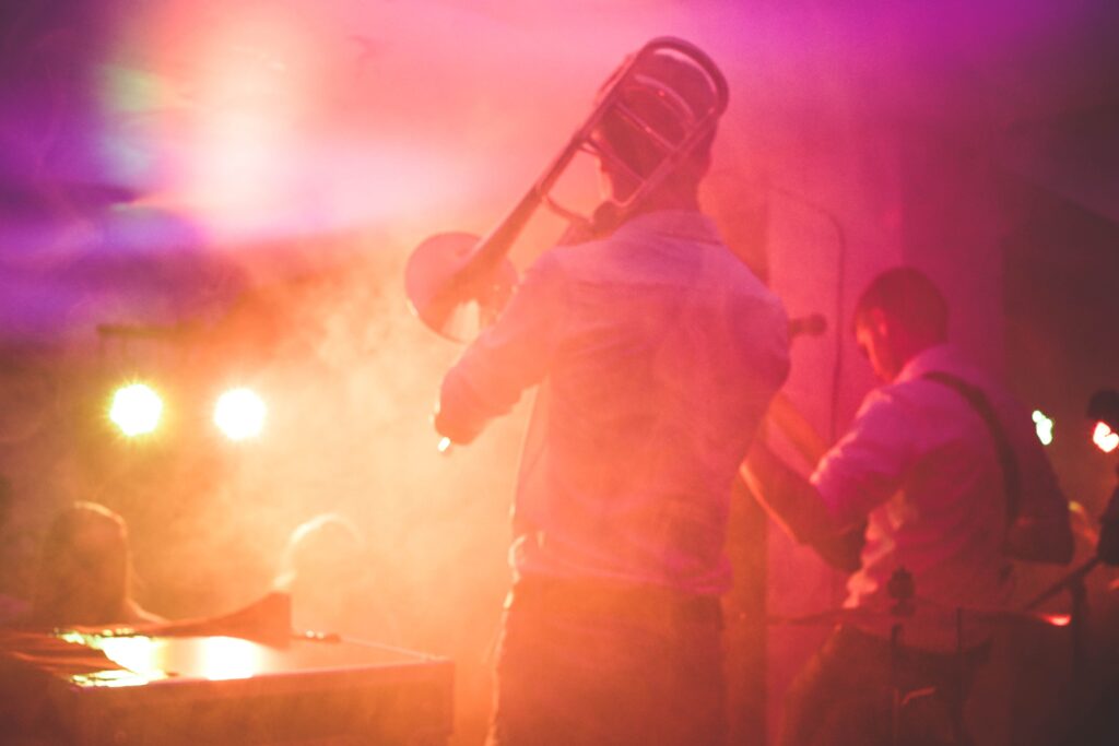 Musicians playing a trombone on stage under bright neon warm lights, offering unexpected hometown date choices.