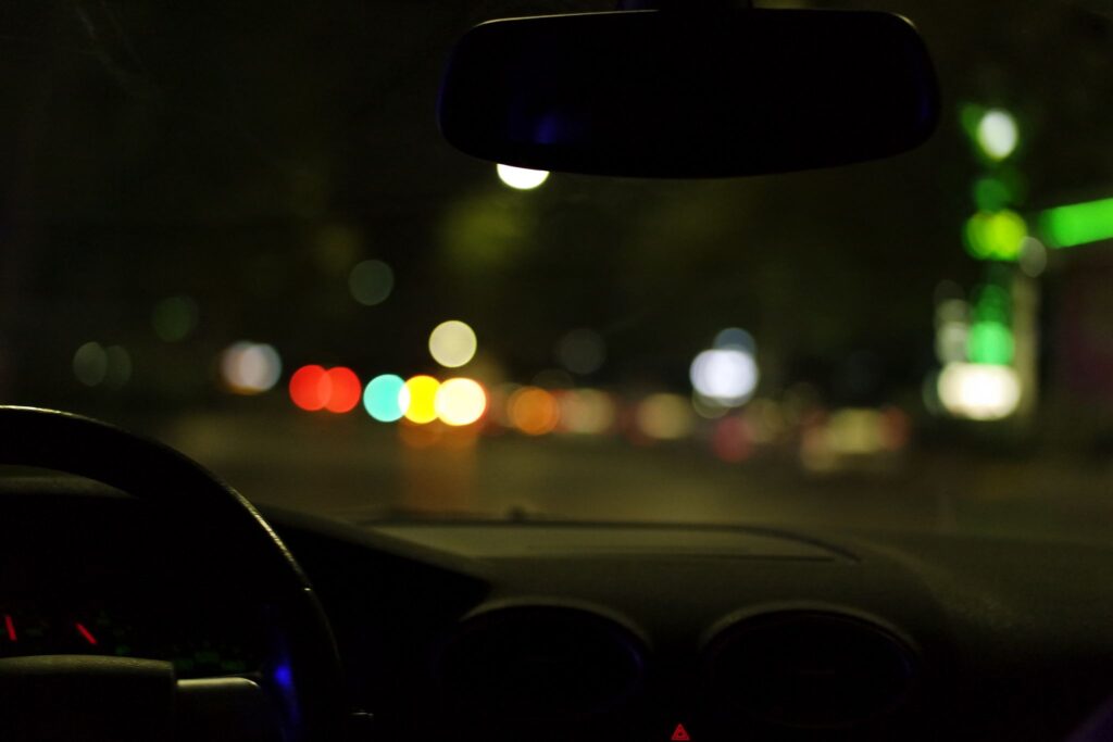View from a car dashboard at night looking out at blurry city lights during romantic follow-up dates.