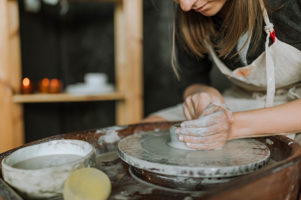 Close up of hands shaping wet clay on a spinning wheel during creative relationship milestones. 
