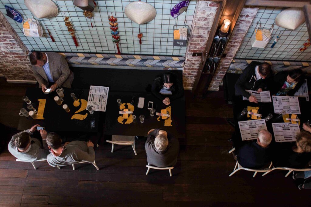 Top view of a lively bar setting with people sitting at tables for introductory meetups. 