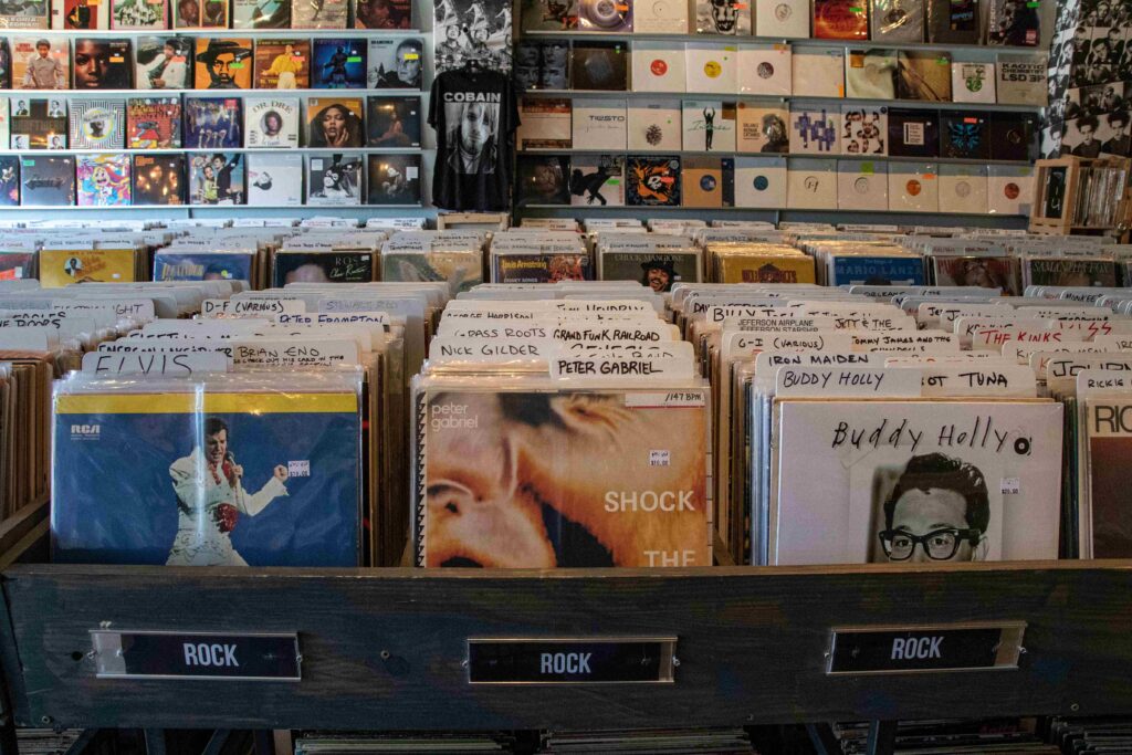 A close up of fingers flipping through a rack of vintage vinyl albums during second nostalgic meetups.