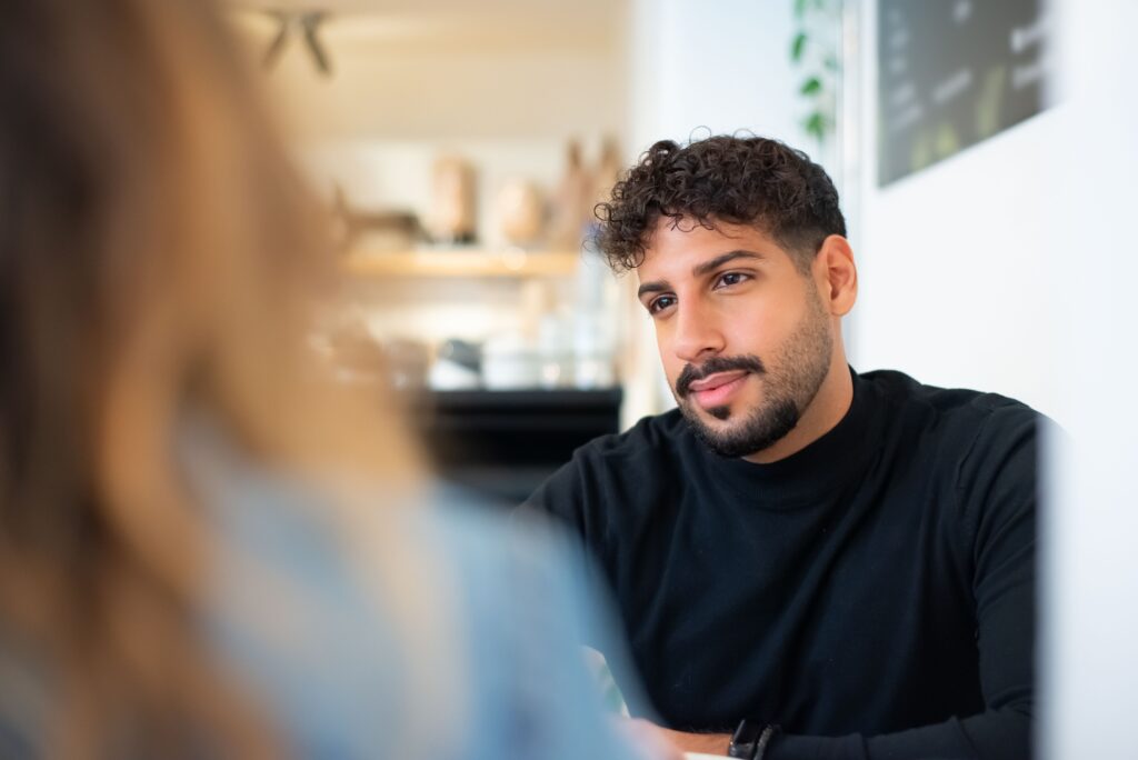 A man listening thoughtfully to a blurred friend, showing the need for validation over parental disconnect.