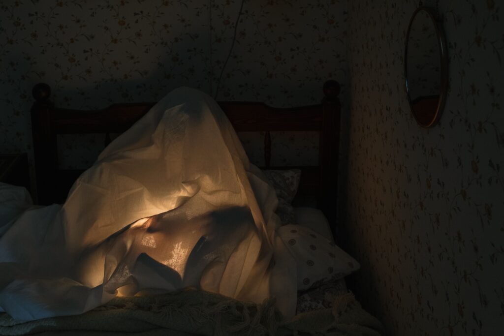 Dark Pick Up Lines: Use These Only If You’re 100% Sure They Share Your Exact Twisted Sense of Humor A person glowing under a bedsheet like a ghost, ready to share playful dark pick up lines.
