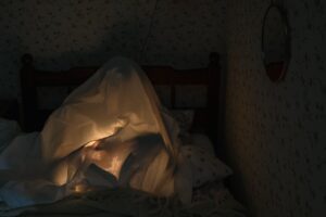 A person glowing under a bedsheet like a ghost, ready to share playful dark pick up lines.