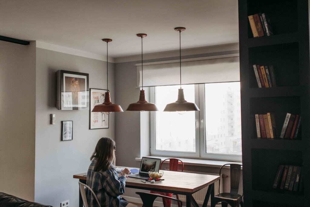 Woman sitting alone at a table working on a laptop, reflecting modern dating in your 30s.