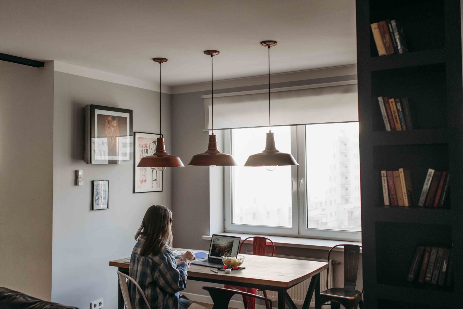 Woman sitting alone at a table working on a laptop, reflecting modern dating in your 30s.