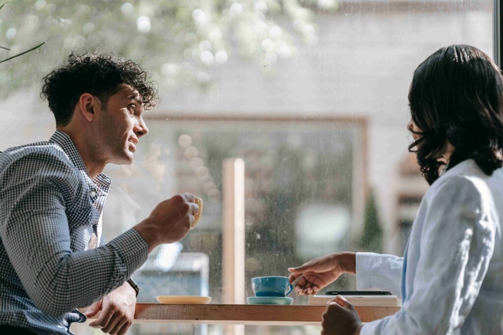 A man chatting with a woman by a window, testing out some unhinged tier openers with a calm delivery. 