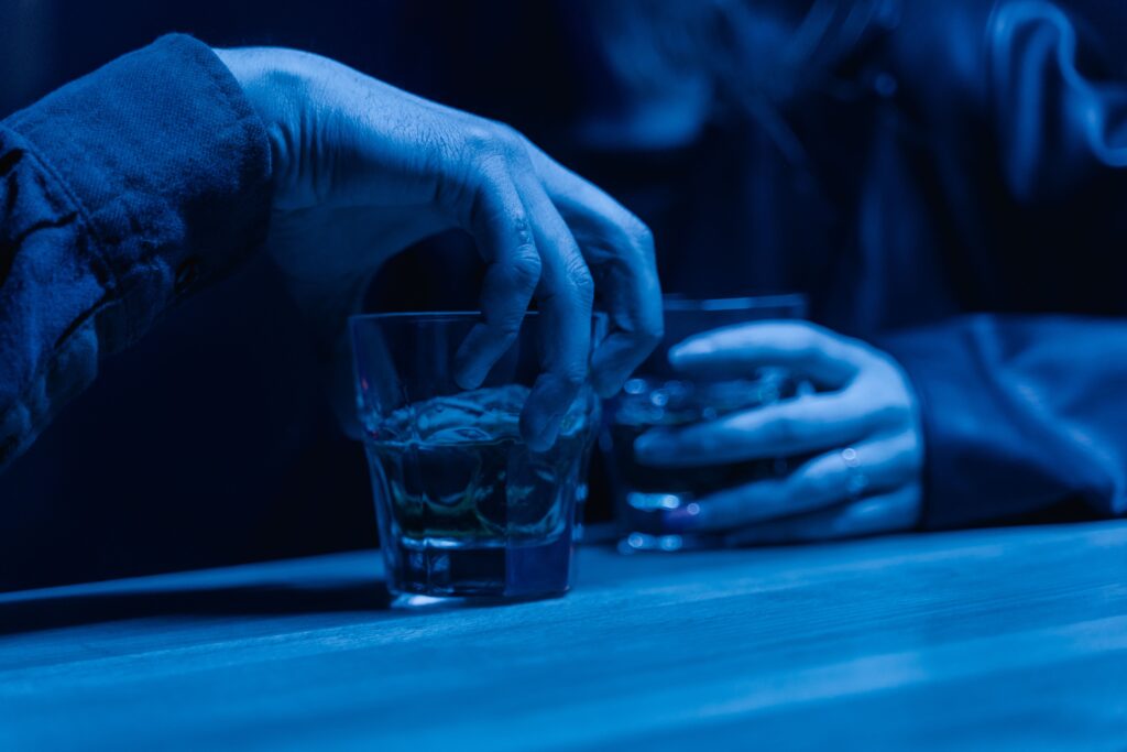 Dirty Pick Up Lines: Use These Only If You Are Completely Done Being Polite and Want to Set the Mood Right Away Hands holding drinks under blue lights, perfect for setting a romantic mood with dirty pick up lines.