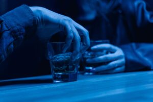 Dirty Pick Up Lines: Use These Only If You Are Completely Done Being Polite and Want to Set the Mood Right Away Hands holding drinks under blue lights, perfect for setting a romantic mood with dirty pick up lines.
